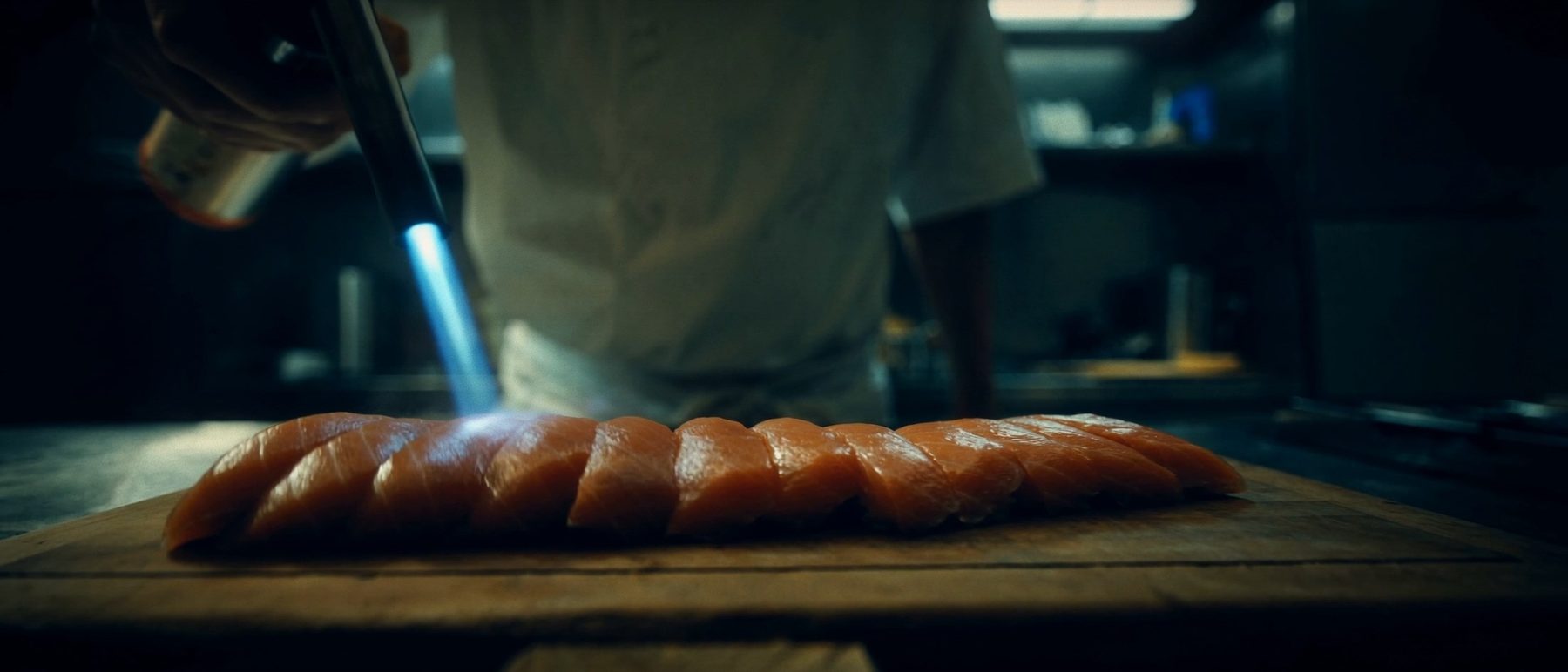 A row of nigiri lined up under warm overhead light