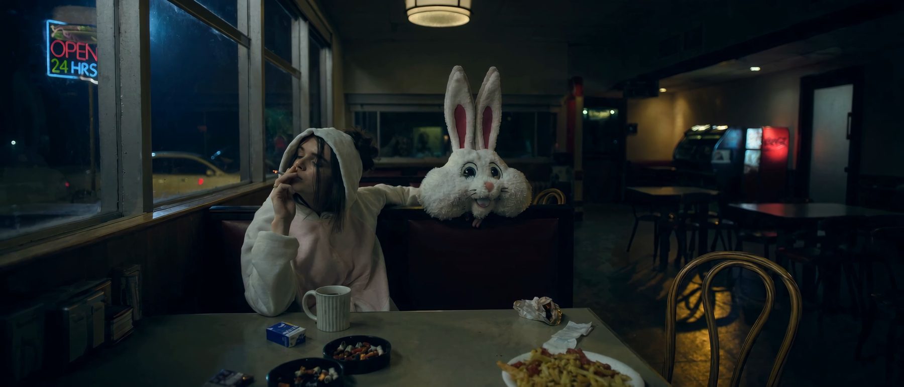 A tired young woman on a smoke break in an empty diner
