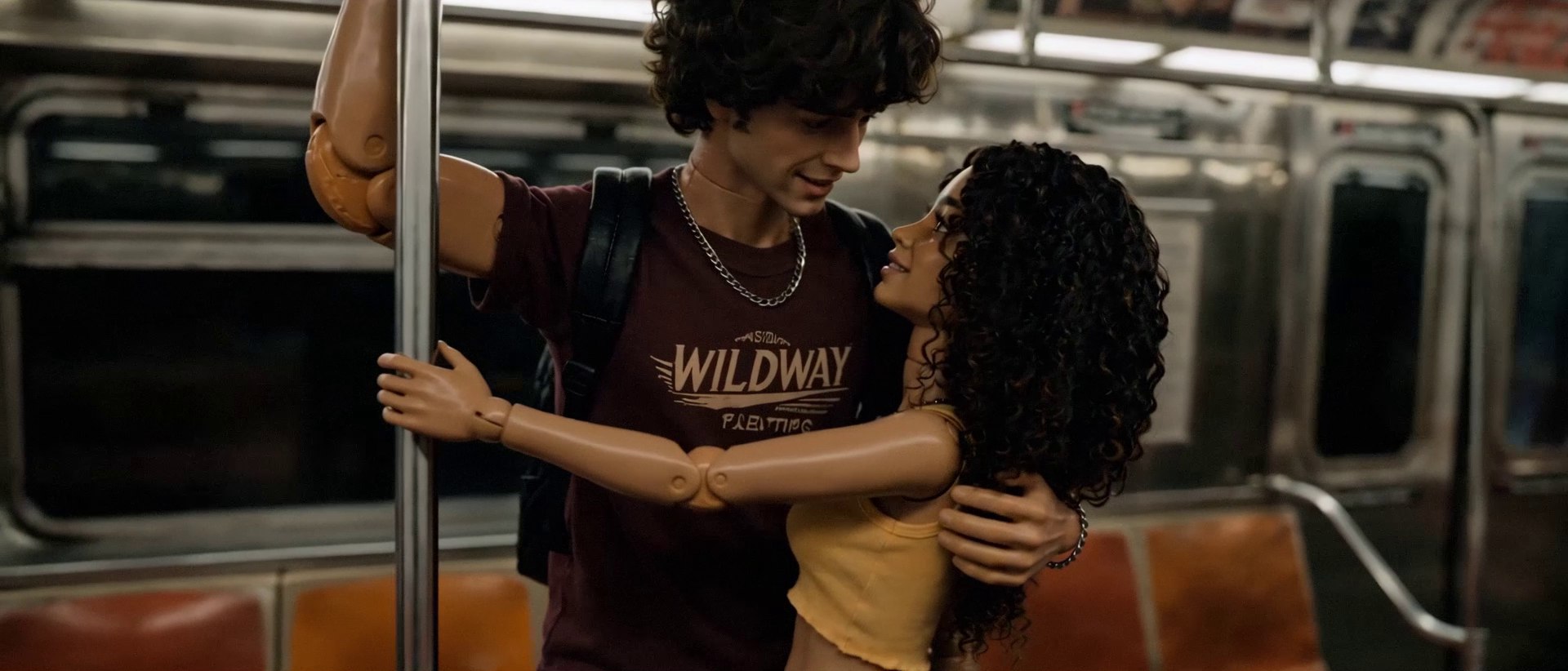 The couple hold each other by a pole in a moving subway car, looking into each other's eyes