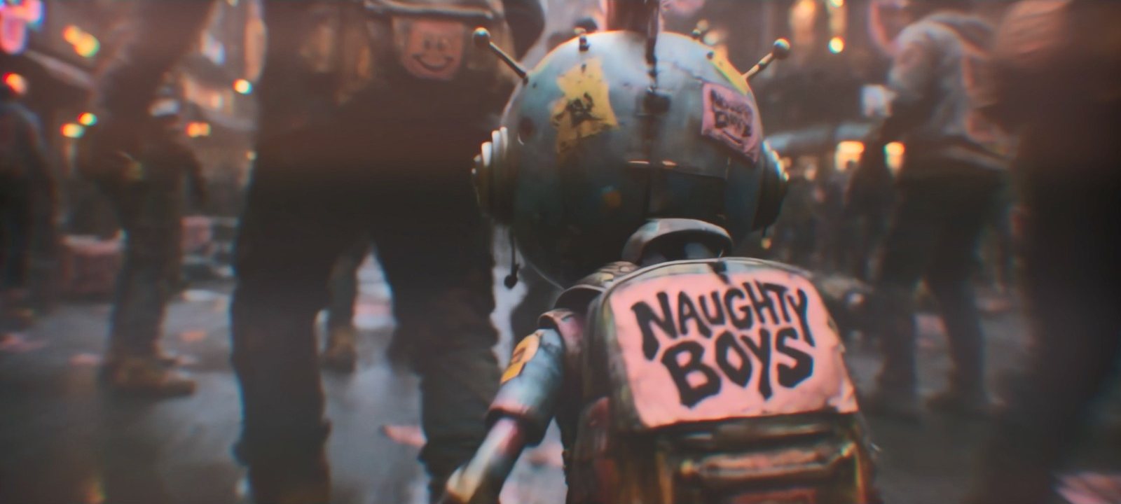 From behind, the antenna-headed mascot walks into a dense street crowd, a Naughty Boys patch stitched to its backpack
