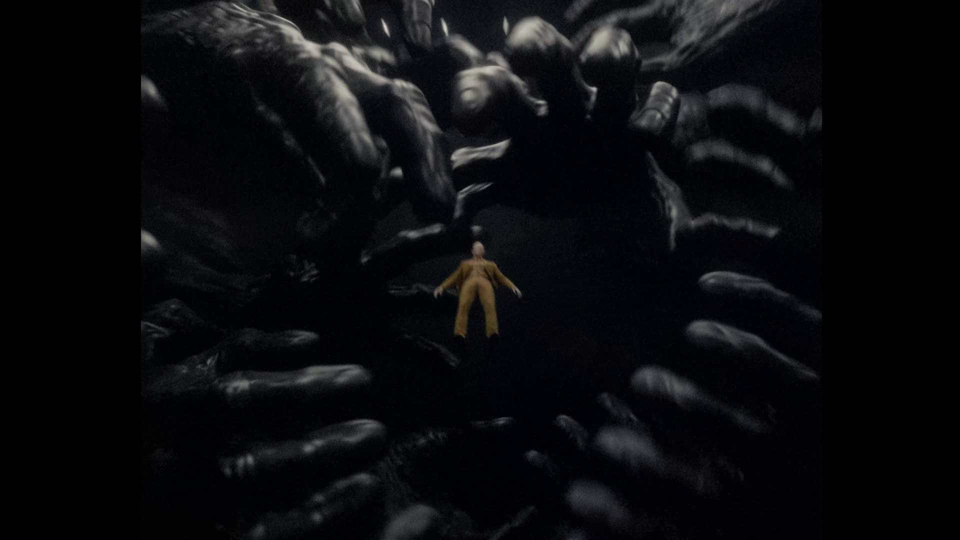 The tiny mustard-suited figure stands in a pit surrounded by enormous black hands reaching in from every side